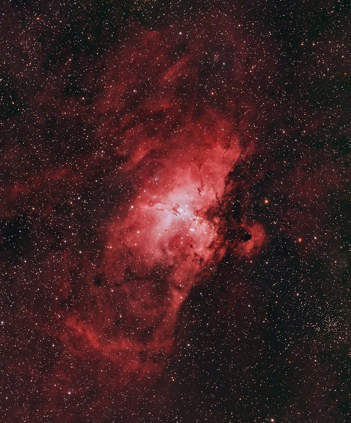 about-us-02 A vivid nebula with bright red hues against the starry night sky.