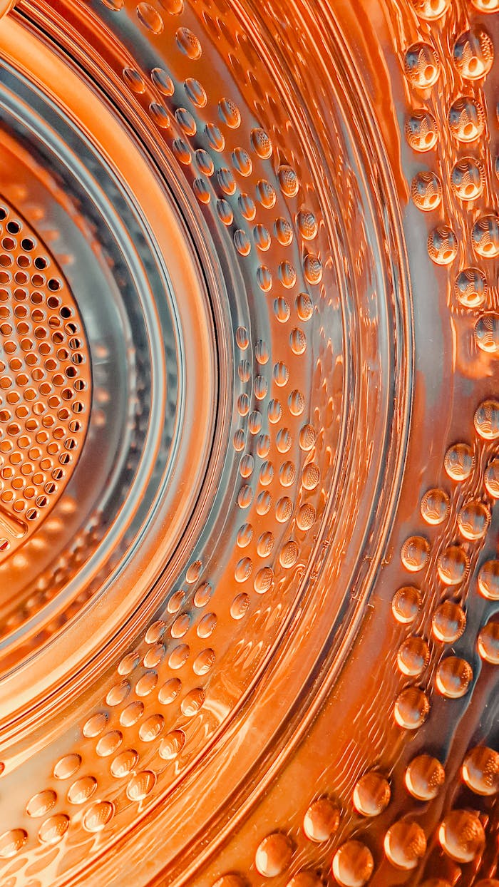 Dynamic close-up of a washing machine drum with vibrant orange lighting and textures.